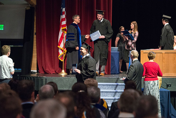 Convocation for College of Physical Sciences and Engineering in the Hart Auditorium.  Graduates receive their diploma covers.