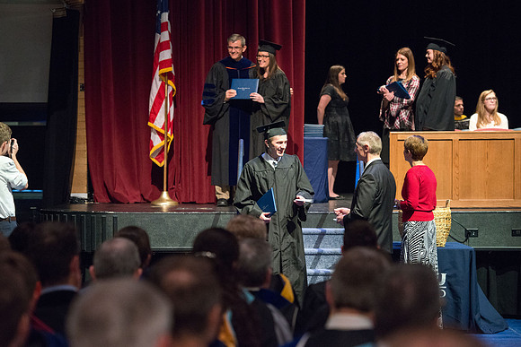 Convocation for College of Physical Sciences and Engineering in the Hart Auditorium.  Graduates receive their diploma covers.