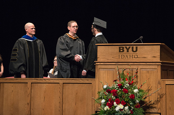 Convocation for College of Physical Sciences and Engineering in the Hart Auditorium.  Graduates receive their diploma covers.
