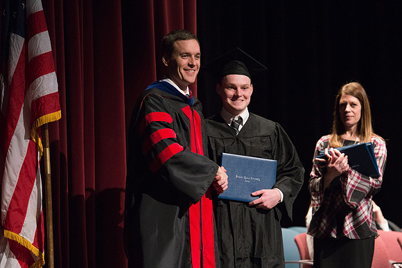 Convocation for College of Physical Sciences and Engineering in the Hart Auditorium.  Graduates receive their diploma covers.