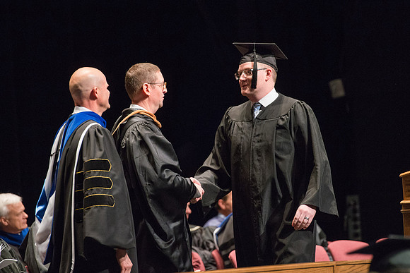 Convocation for College of Physical Sciences and Engineering in the Hart Auditorium.  Graduates receive their diploma covers.
