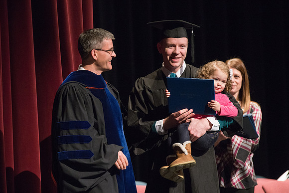 Convocation for College of Physical Sciences and Engineering in the Hart Auditorium.  Graduates receive their diploma covers.