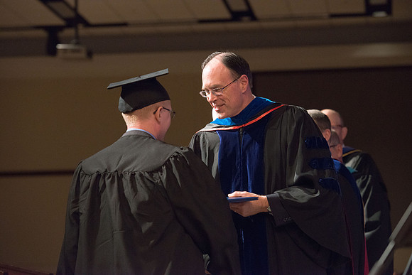 Convocation for College of Language and Letters.  Bishop W. Christopher Waddell and President Henry J Eyring present the graduates with their diploma covers.