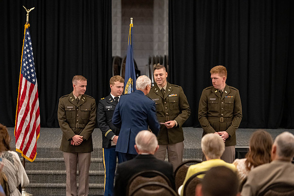 Four graduates from the BYU-Idaho ROTC program gather with the families and have a ceremonial commissioning.