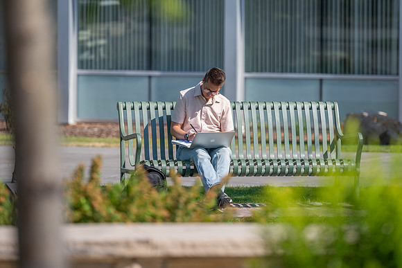 Student studies on campus bench in Taylor Quad