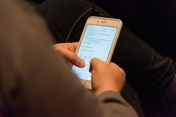 Student parent makes note on the phone during the parent session of Secrets for Students Success.