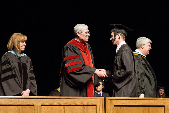 Edwin A. Sexton shakes hands with a Communication graduate in the Hart Auditorium during Convocation.
