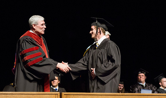 Edwin A. Sexton shakes hands with a graduate from the College of Business and Communication in the Hart Auditorium during Convocation.