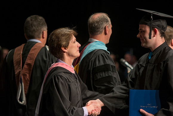 Faculty members hand degrees to and congratualate graduates of the College of Performing and Visual Arts.