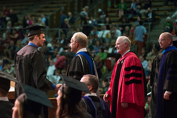 Elder W. Craig Zwick and President Kim B. Clark award diploma covers to graduates in the College of Business and Communication.