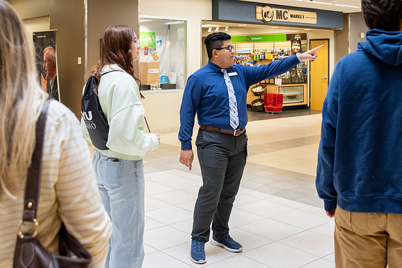 Employee giving a tour around campus to prospective students and their parents.