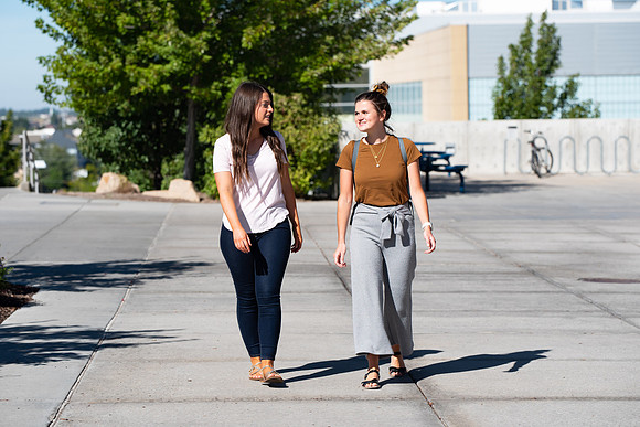 Examples of students staying safe and healthy during the COVID-19 pandemic by social distancing, following pathway arrows, and wearing face masks.