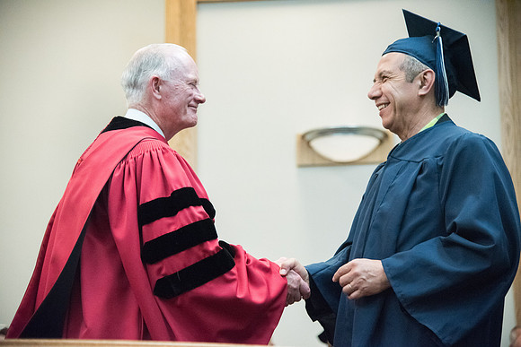 Graduates shake Elder Kim B. Clark's hand before being awarded their Diploma at Convocation of the Sociology and Social Work/Psychology in the Hinckley Chapel. July 2018