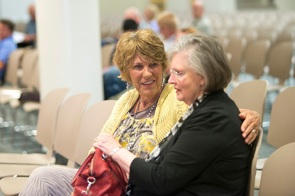 Friends laugh together while waiting for devotional to start.
