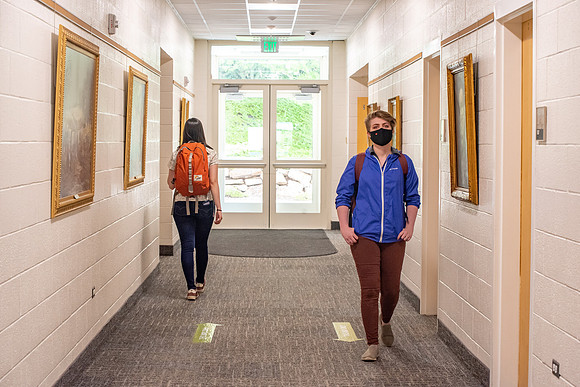 Examples of students staying safe and healthy during the COVID-19 pandemic by social distancing, following pathway arrows, and wearing face masks.