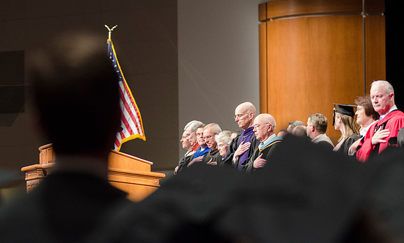 BYU-I staff respect the posting of the American Flag by placing the right hand over the heart during the 2014 Winter Semster Graduation Commencement in the I-Center.