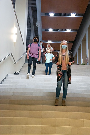 Examples of students staying safe and healthy during the COVID-19 pandemic by social distancing, following pathway arrows, and wearing face masks.