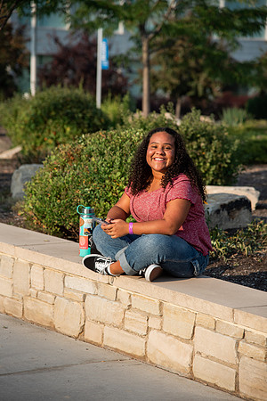 Student on her phone on campus between the Taylor and Manwaring Center.