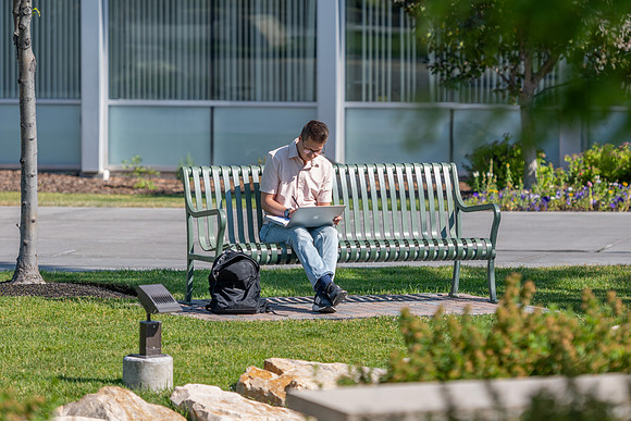 Student studies on campus bench in Taylor Quad