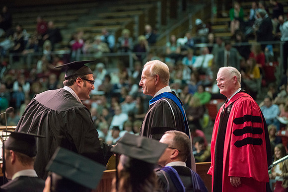 Elder W. Craig Zwick and President Kim B. Clark award diploma covers to graduates in the College of Business and Communication.