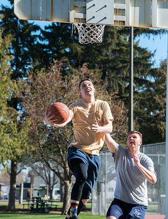 Jacob Kaiser (in yellow) playing basketball, one on one with Jacob Madsen at Smith Park in Rexburg, Idaho.