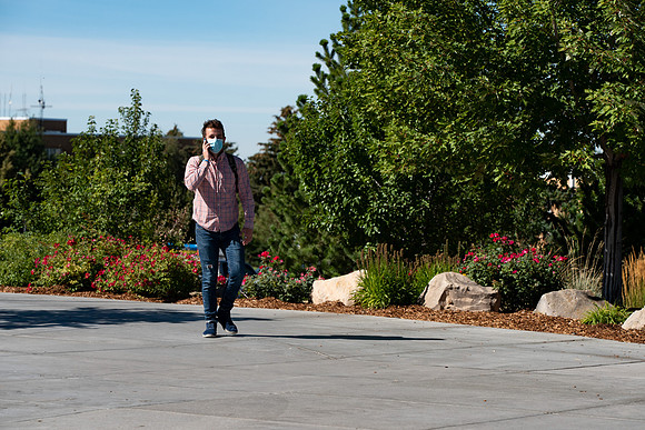 Examples of students staying safe and healthy during the COVID-19 pandemic by social distancing, following pathway arrows, and wearing face masks.