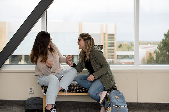 Students laugh together on the skybridge between the McKay Library and the Manwaring Center.