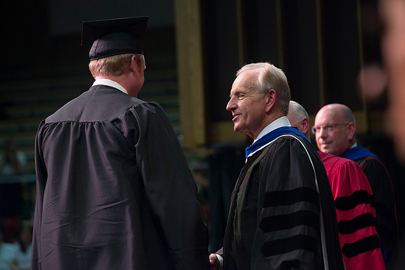 Elder W. Craig Zwick and President Kim B. Clark award diploma covers to graduates in the College of Business and Communication.