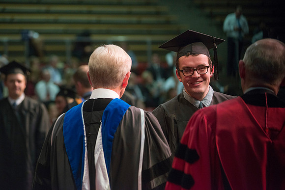 Elder W. Craig Zwick and President Kim B. Clark award diploma covers to graduates in the College of Business and Communication.