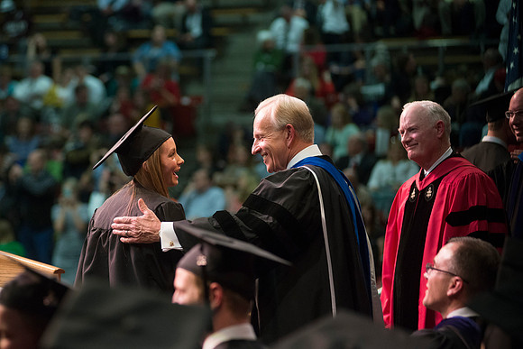 Elder W. Craig Zwick and President Kim B. Clark award diploma covers to graduates in the College of Business and Communication.