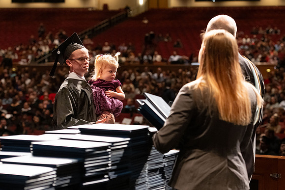 Graduates walk across the stage and accept their diploma.