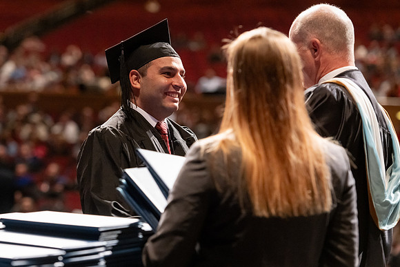 Graduates walk across the stage and accept their diploma.