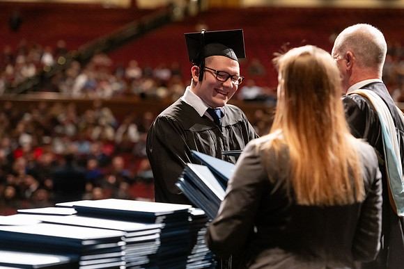 Graduates walk across the stage and accept their diploma.