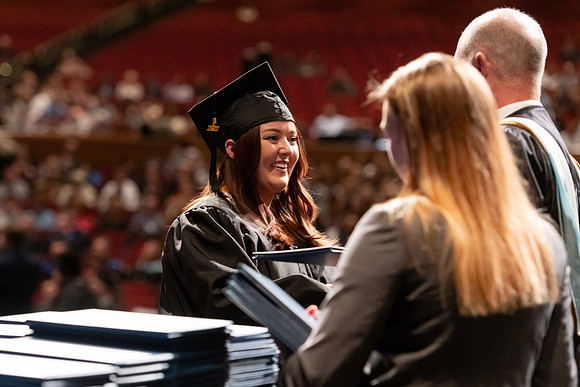 Graduates walk across the stage and accept their diploma.
