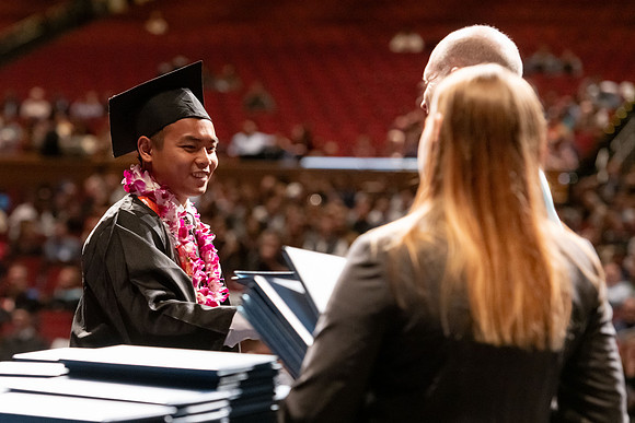 Graduates walk across the stage and accept their diploma.