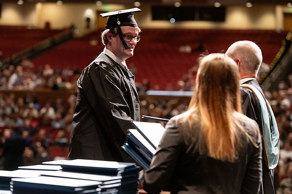Graduates walk across the stage and accept their diploma.