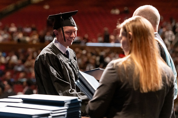 Graduates walk across the stage and accept their diploma.