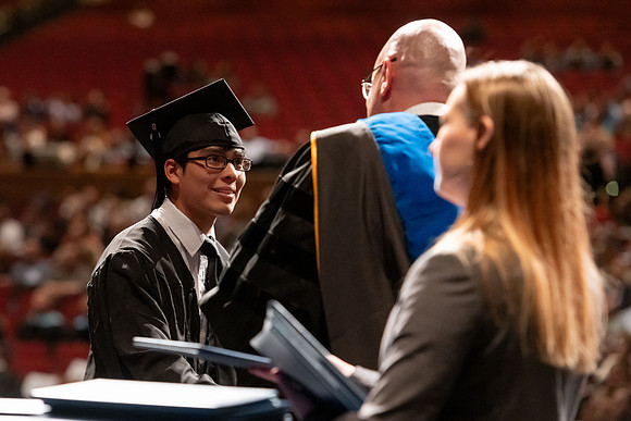 Graduates walk across the stage and accept their diploma.