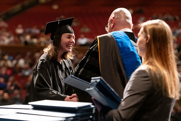 Graduates walk across the stage and accept their diploma.