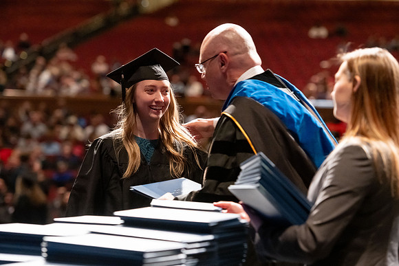 Graduates walk across the stage and accept their diploma.