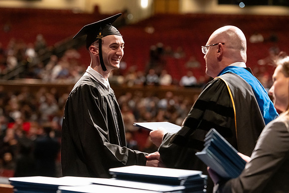 Graduates walk across the stage and accept their diploma.