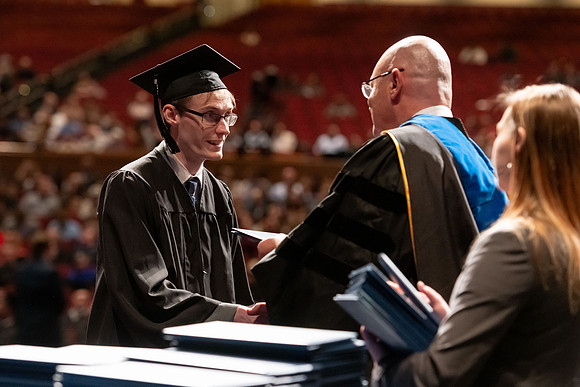 Graduates walk across the stage and accept their diploma.