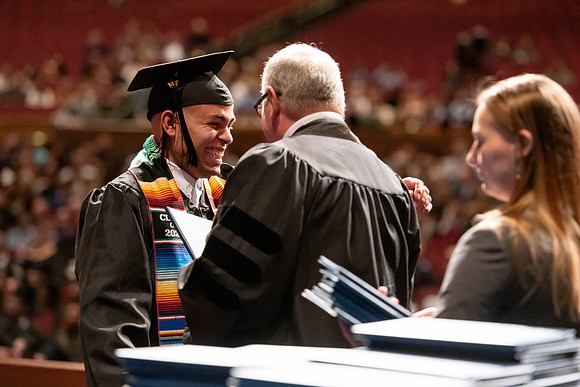 Graduates walk across the stage and accept their diploma.