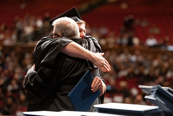 Graduates walk across the stage and accept their diploma.