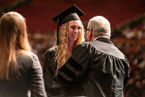 Graduates walk across the stage and accept their diploma.