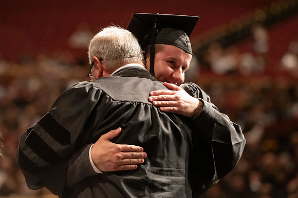 Graduates walk across the stage and accept their diploma.