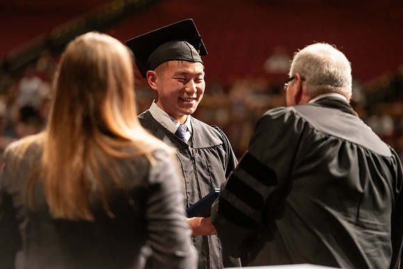 Graduates walk across the stage and accept their diploma.