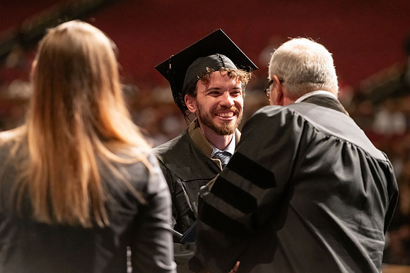Graduates walk across the stage and accept their diploma.