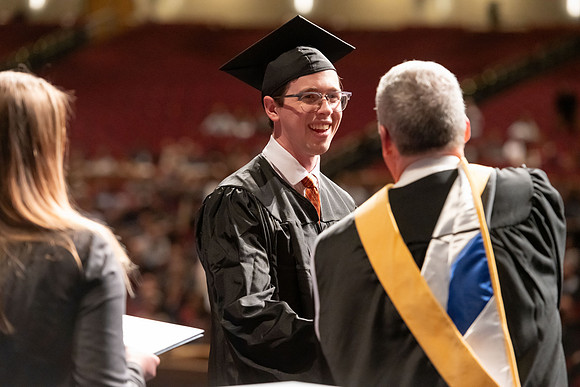 Graduates walk across the stage and accept their diploma.