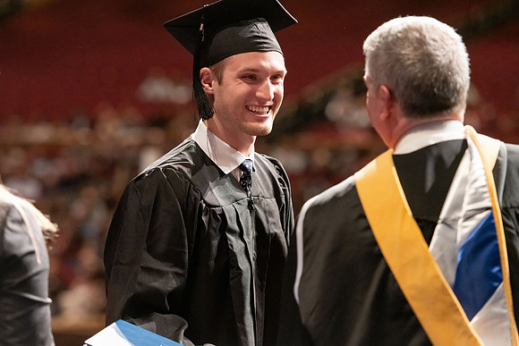 Graduates walk across the stage and accept their diploma.